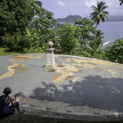 Woman sitting in front of the monument that marks the equator on the island of Las Rolas.